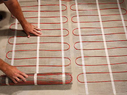 ComfortTile floor heating mats being laid out for a heated floor system.